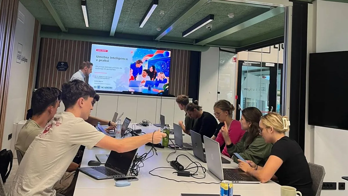 Participants of an AI workshop at Impact Hub Ljubljana sitting with laptops along a long table, a slide on the screen behind them